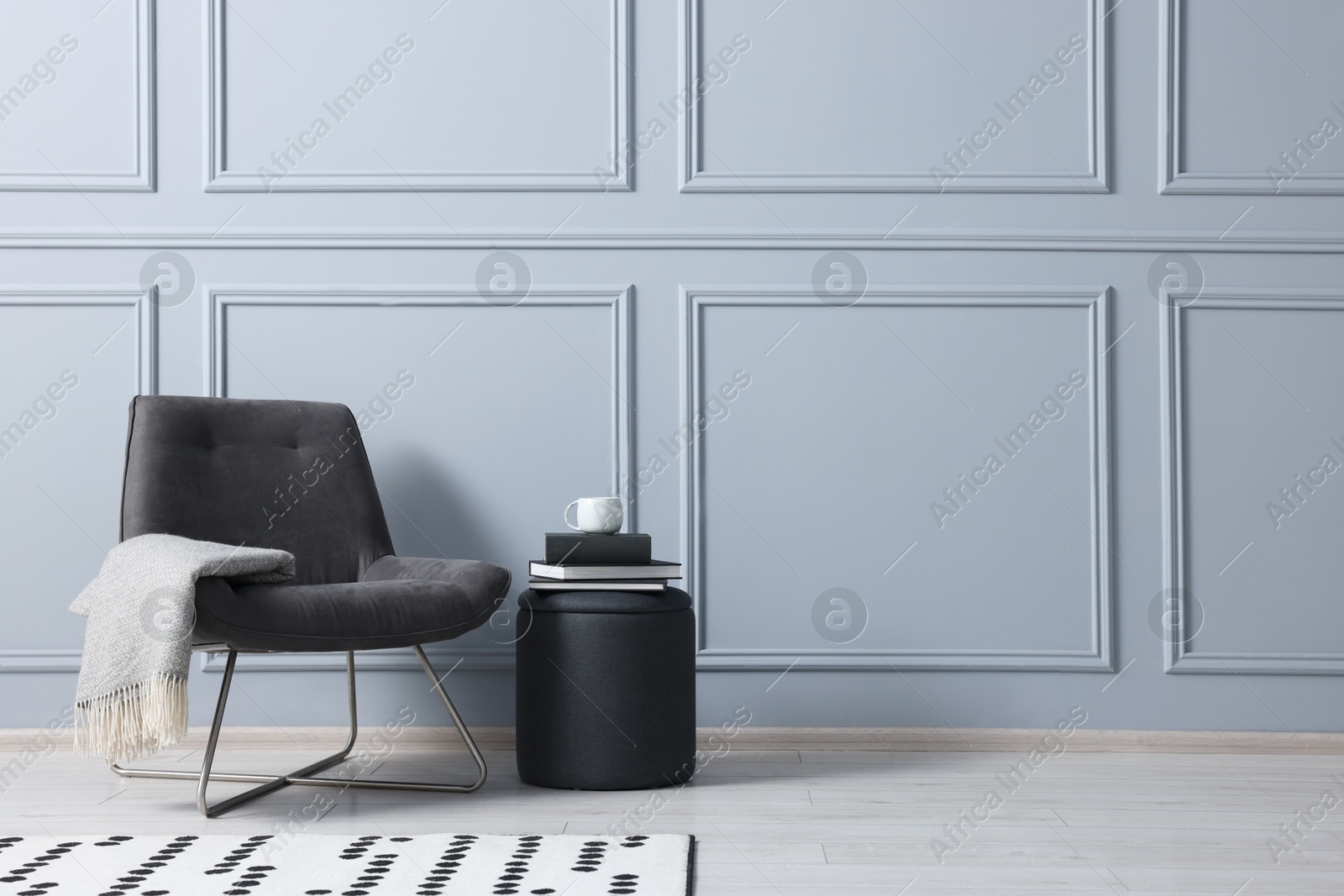 Photo of Stylish stool, chair and books near light grey wall indoors, space for text