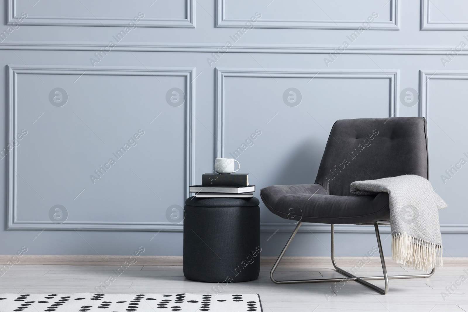 Photo of Stylish stool, chair and books near light grey wall indoors, space for text