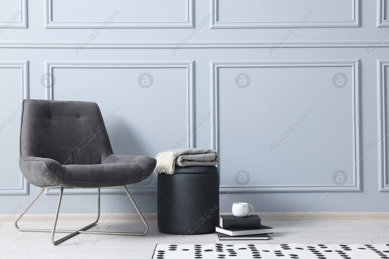 Photo of Stylish stool, chair and books near light grey wall indoors, space for text