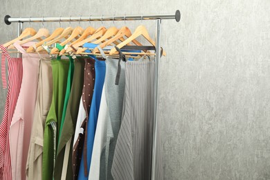 Many chef's aprons on clothing rack near light grey wall, space for text