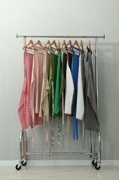 Aprons on clothing rack near light grey wall