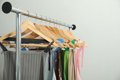 Many chef's aprons on clothing rack near light grey wall, space for text