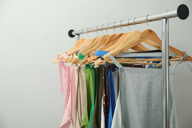 Many chef's aprons on clothing rack near light grey wall, space for text