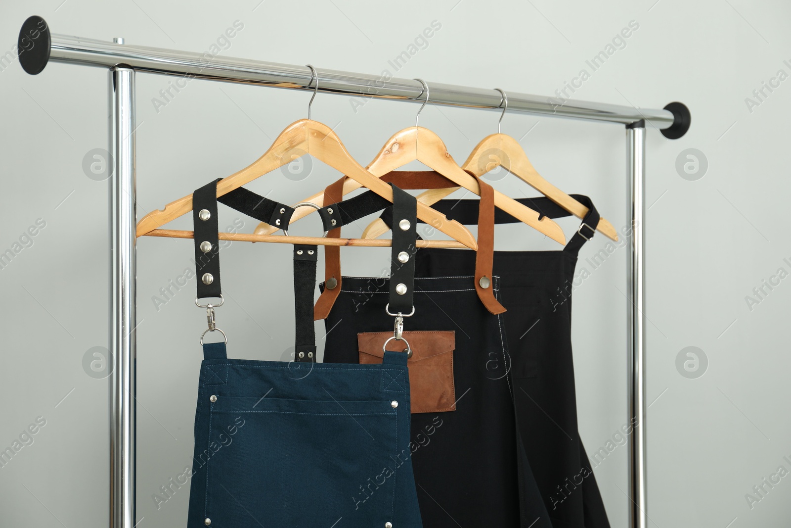 Photo of Aprons on clothing rack near light grey wall