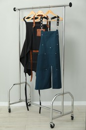 Photo of Aprons on clothing rack near light grey wall