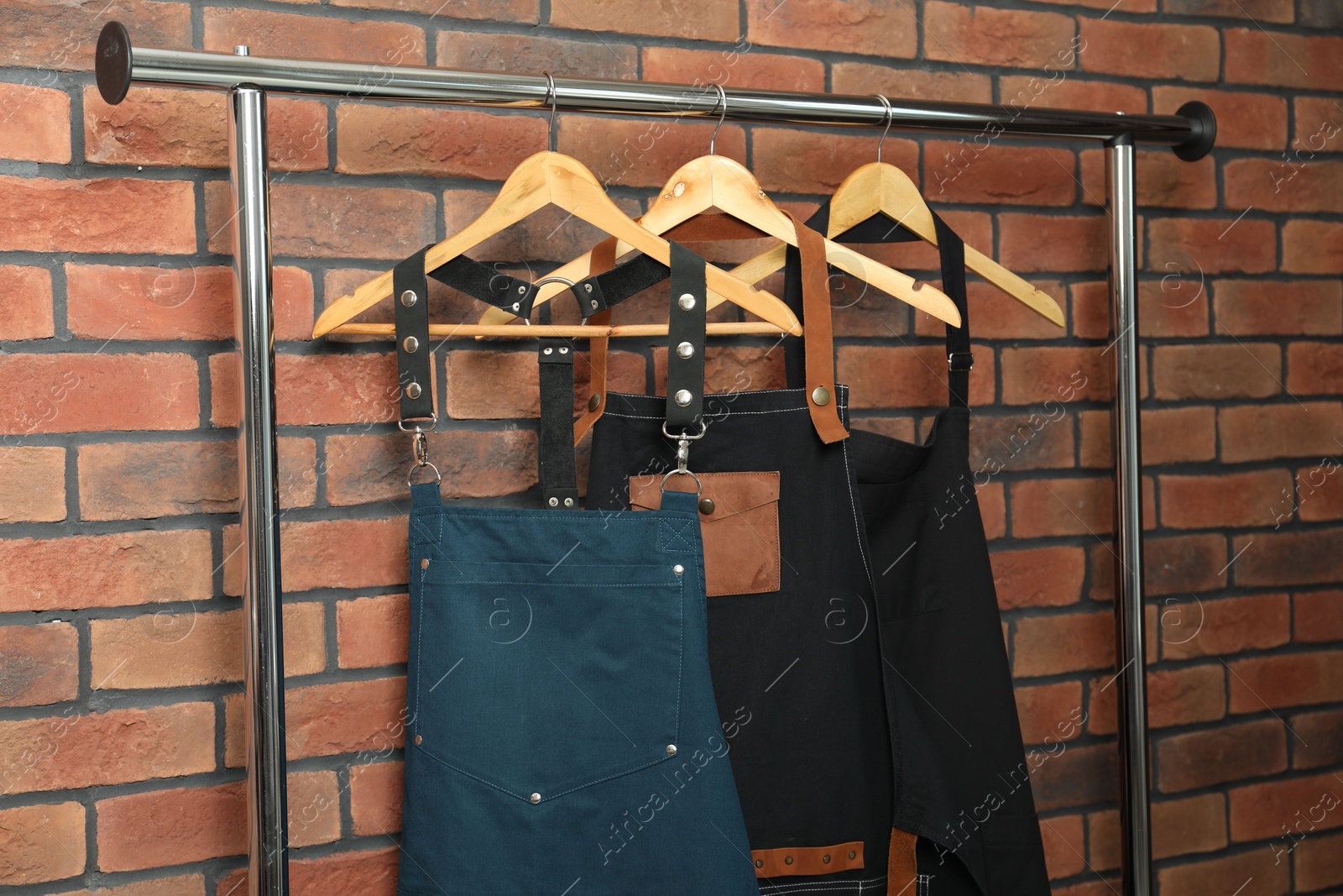 Photo of Many chef's aprons hanging on brick wall