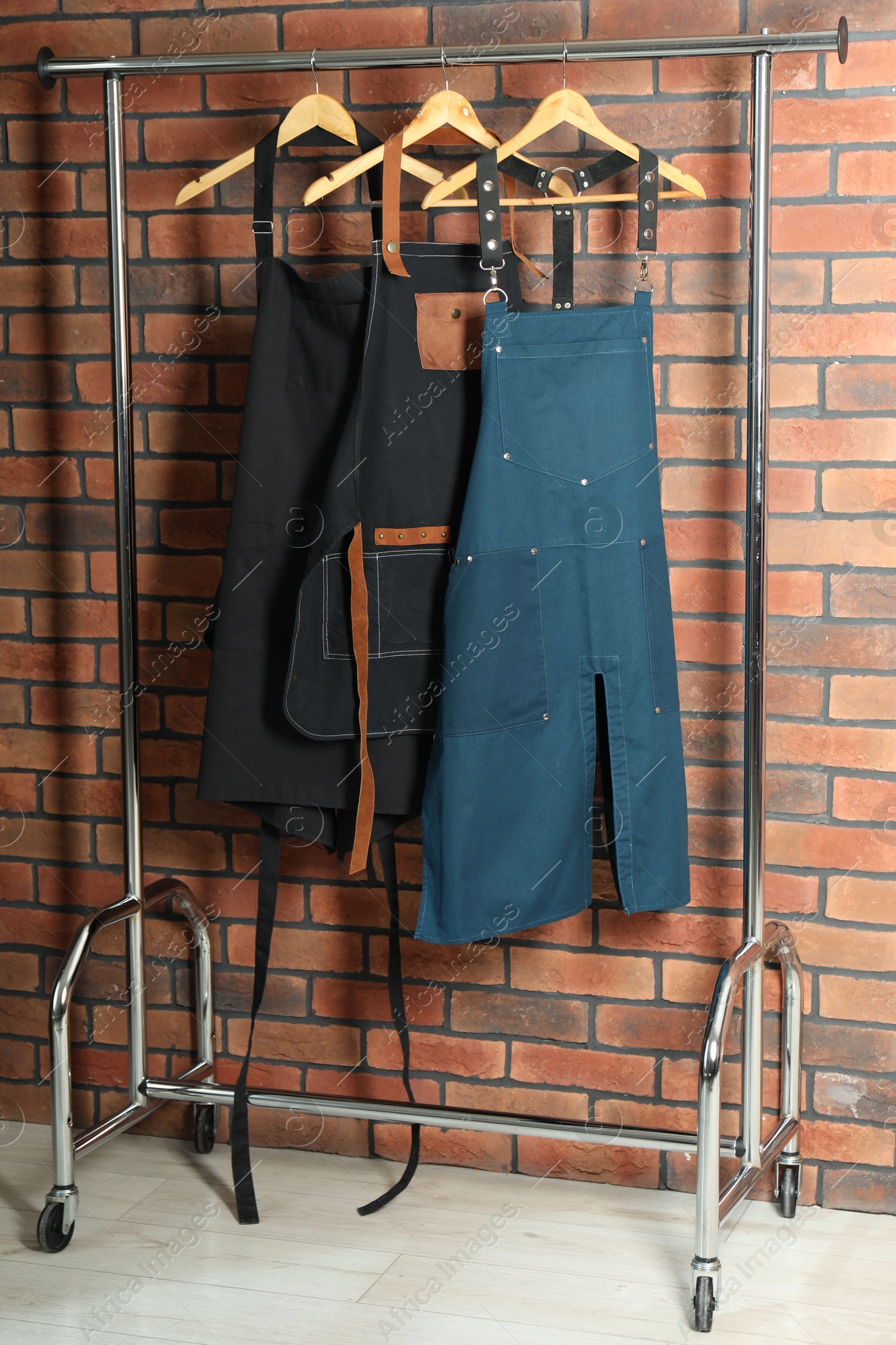 Photo of Many chef's aprons hanging on brick wall