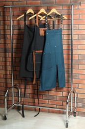 Photo of Many chef's aprons hanging on brick wall