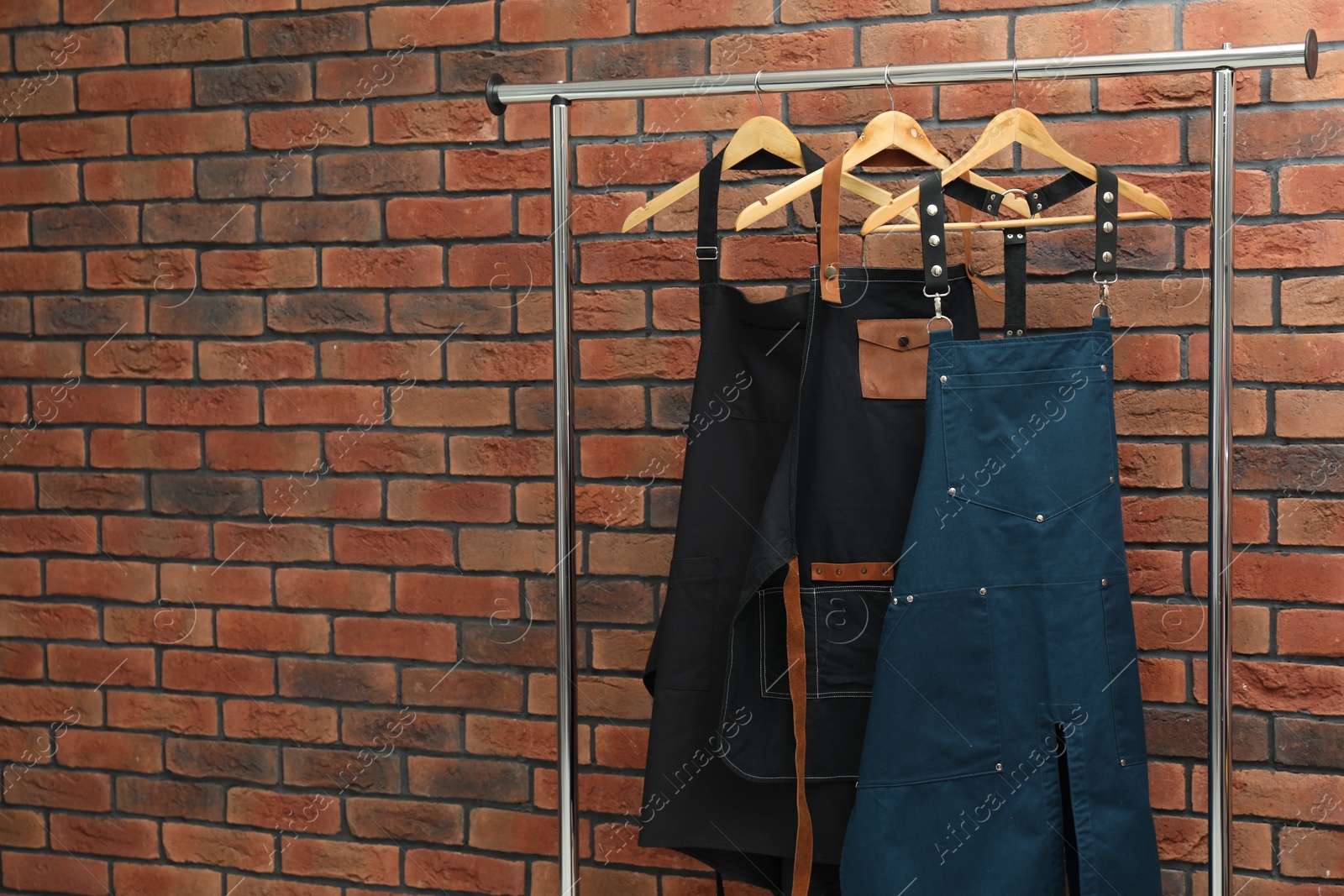 Photo of Many chef's aprons hanging on brick wall