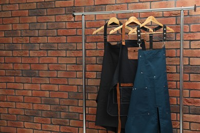 Many chef's aprons hanging on brick wall