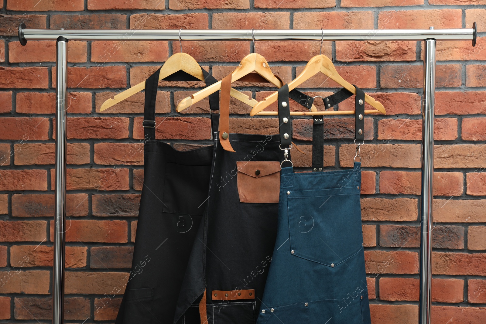 Photo of Many chef's aprons hanging on brick wall