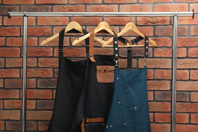 Photo of Many chef's aprons hanging on brick wall