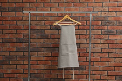 Photo of One chef's apron on clothing rack near brick wall