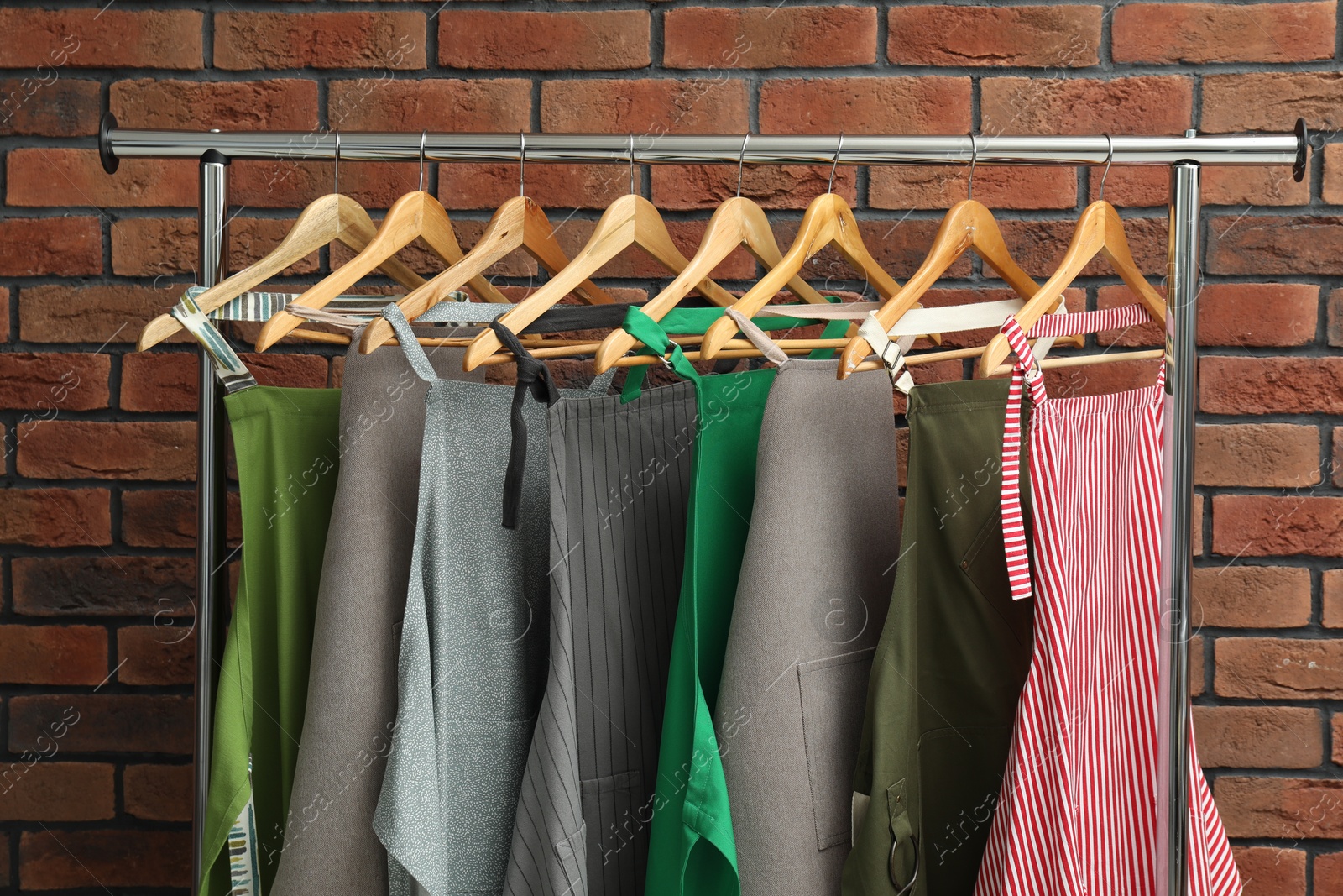 Photo of Many chef's aprons hanging on brick wall