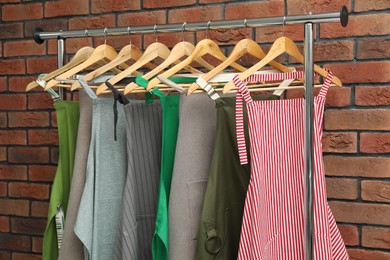 Photo of Many chef's aprons hanging on brick wall