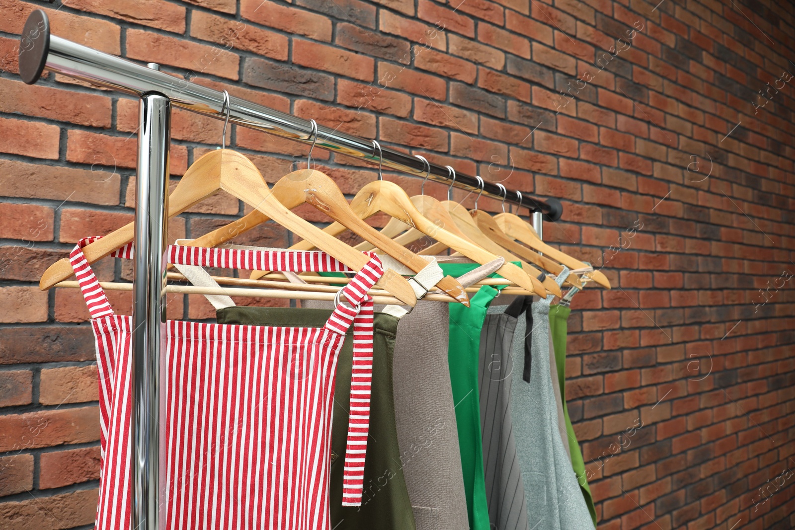 Photo of Many chef's aprons hanging on brick wall