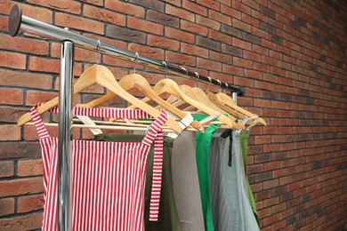 Photo of Many chef's aprons hanging on brick wall