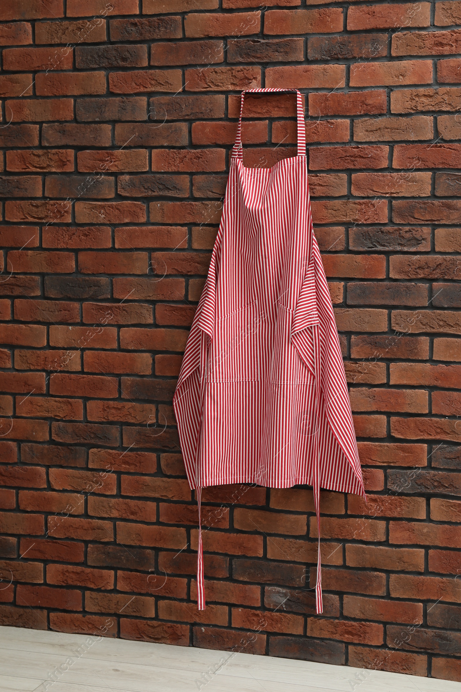 Photo of One chef's apron hanging on brick wall