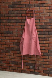 One chef's apron hanging on brick wall