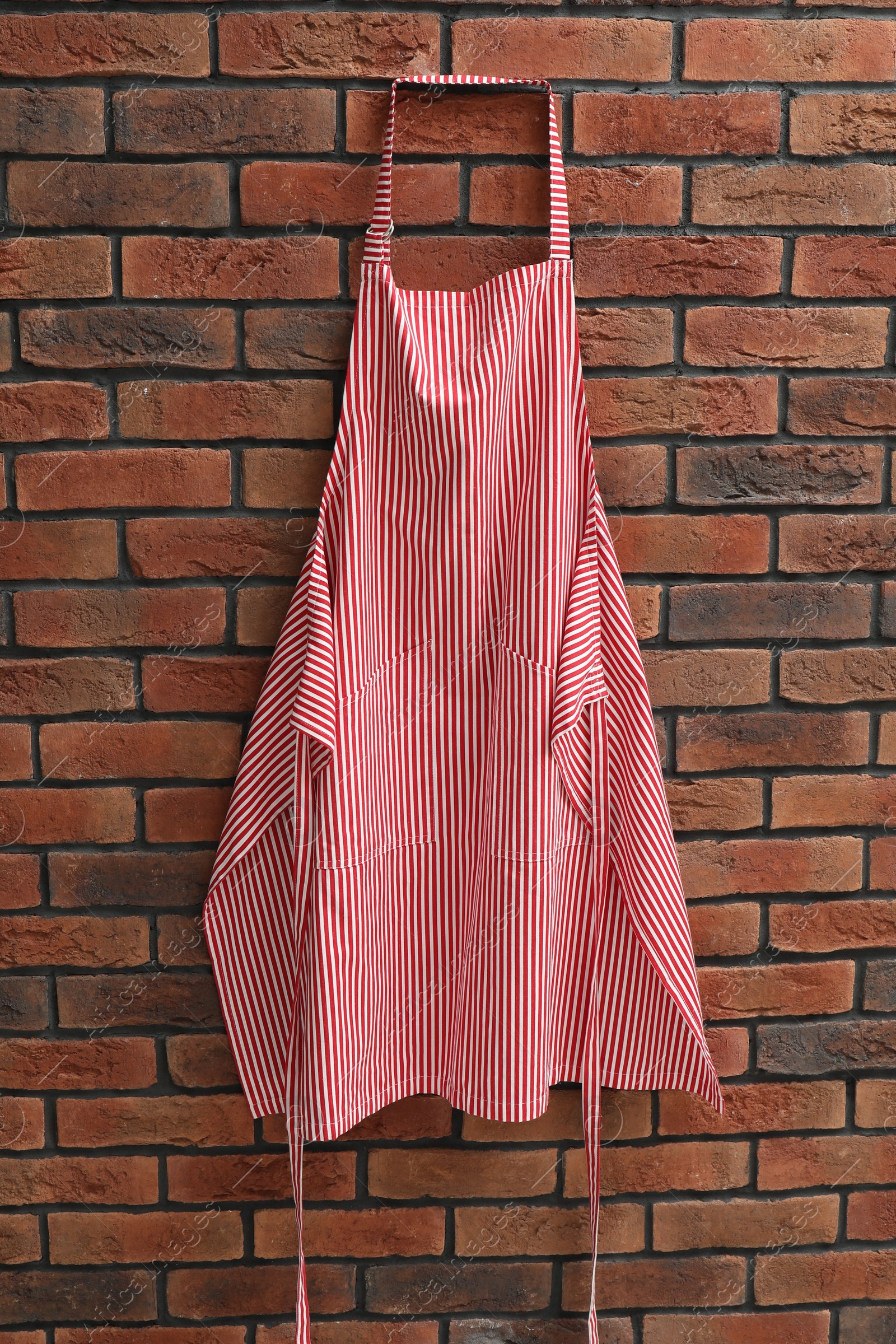 Photo of One chef's apron hanging on brick wall