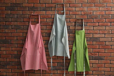 Photo of Many chef's aprons hanging on brick wall