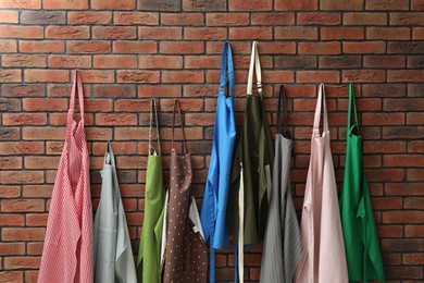 Photo of Many chef's aprons hanging on brick wall