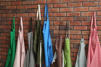 Photo of Many chef's aprons hanging on brick wall