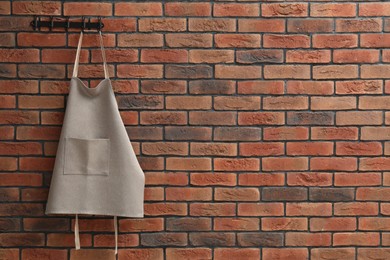 Photo of One chef's apron hanging on brick wall, space for text