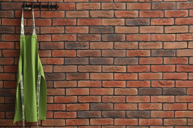 Photo of One chef's apron hanging on brick wall, space for text