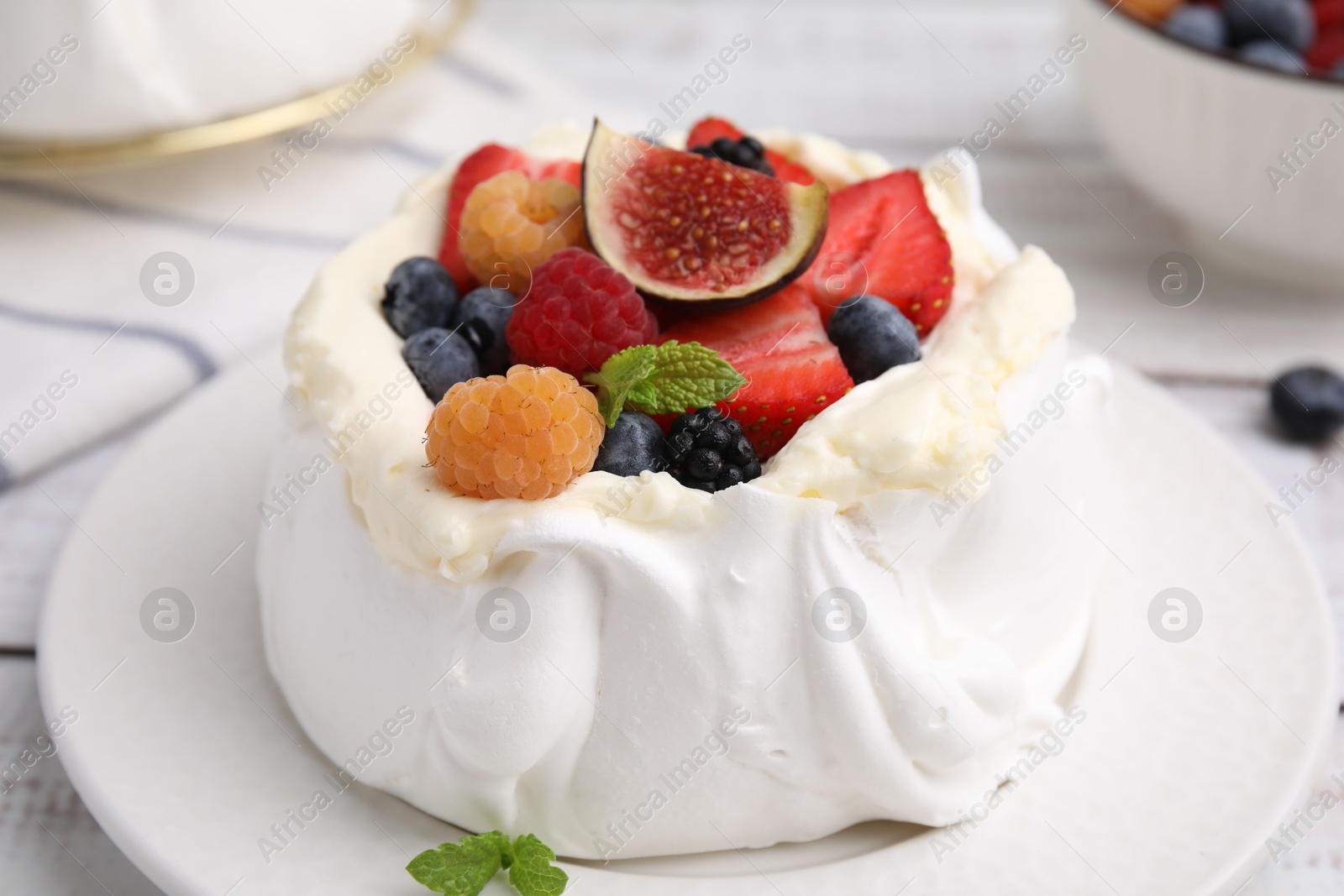 Photo of Pavlova cake (meringue dessert) with whipped cream, fresh berries, fig and mint on table, closeup