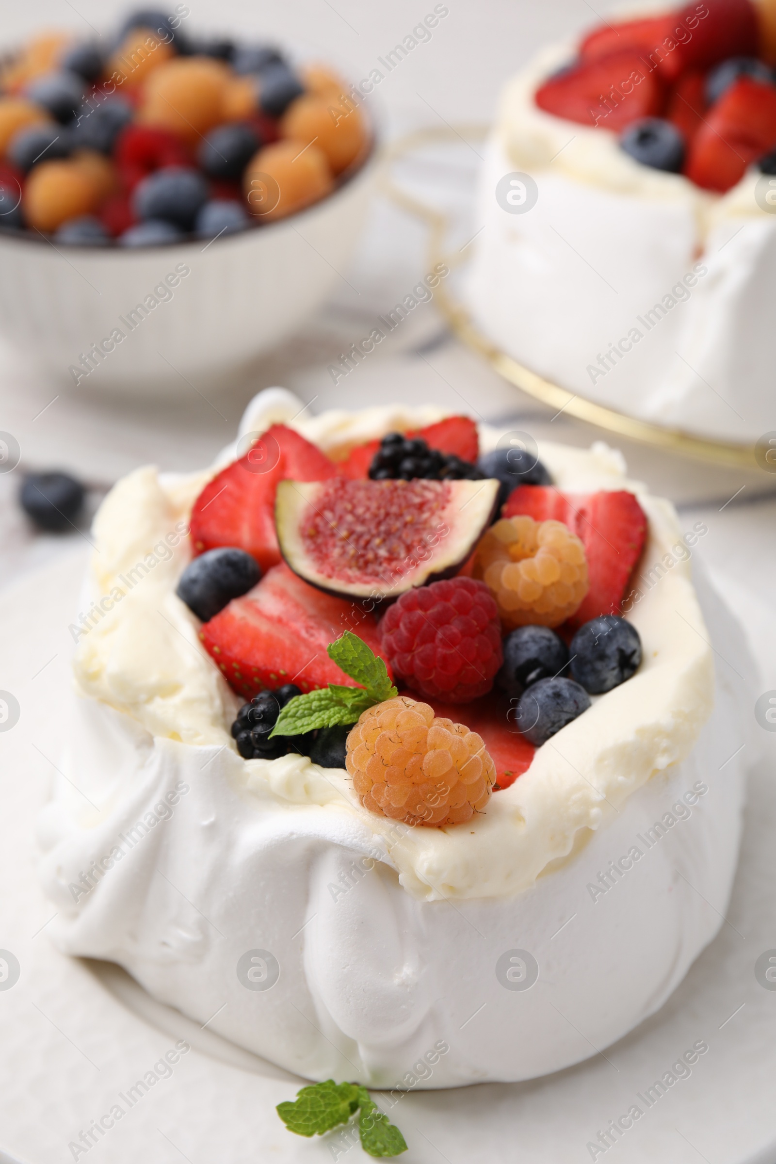 Photo of Pavlova cake (meringue dessert) with whipped cream, fresh berries, fig and mint on table, closeup