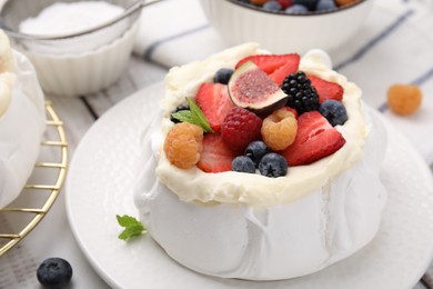 Photo of Pavlova cake (meringue dessert) with whipped cream, fresh berries, fig and mint on table, closeup