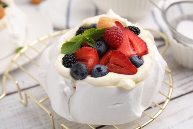 Photo of Pavlova cake (meringue dessert) with whipped cream, fresh berries and mint on white wooden table, closeup