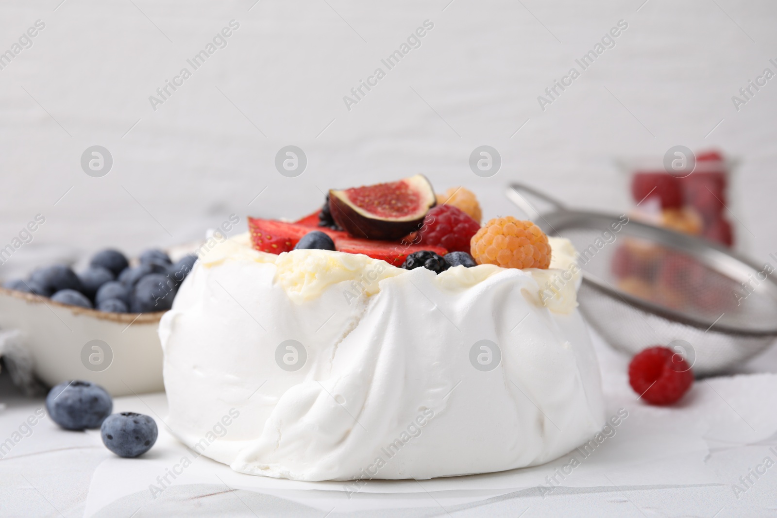 Photo of Pavlova cake (meringue dessert) with whipped cream, fresh berries and fig on table, closeup