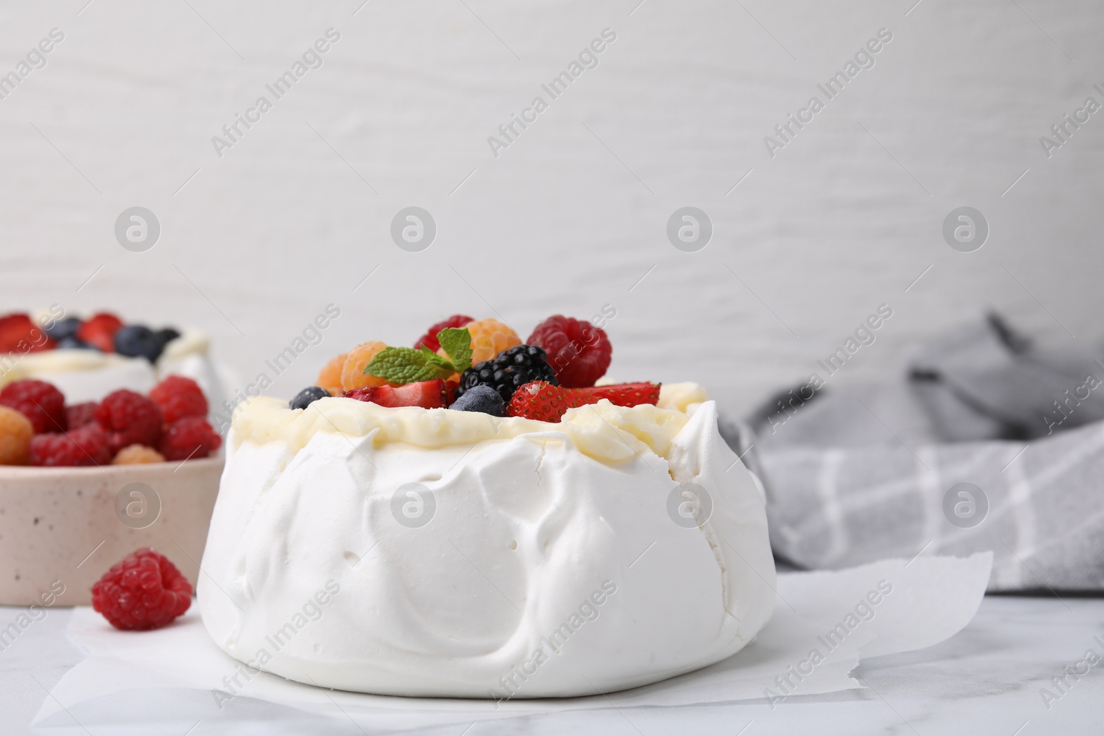 Photo of Pavlova cake (meringue dessert) with whipped cream, fresh berries and mint on white marble table, closeup