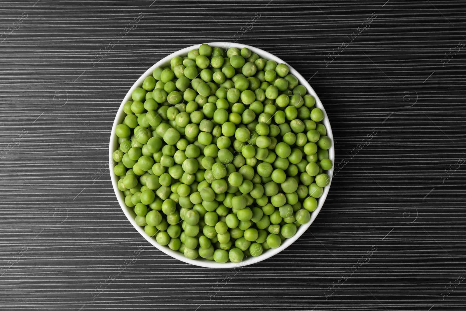 Photo of Fresh green peas on black wooden table, top view