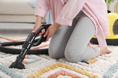 Photo of Woman vacuuming carpet at home, closeup view