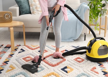 Woman vacuuming carpet in living room, closeup