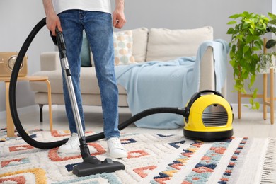 Photo of Man with vacuum cleaning carpet in living room, closeup