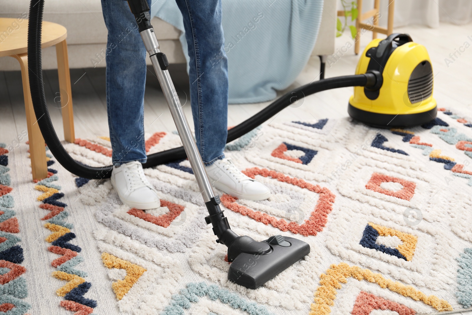 Photo of Man with vacuum cleaning carpet indoors, closeup