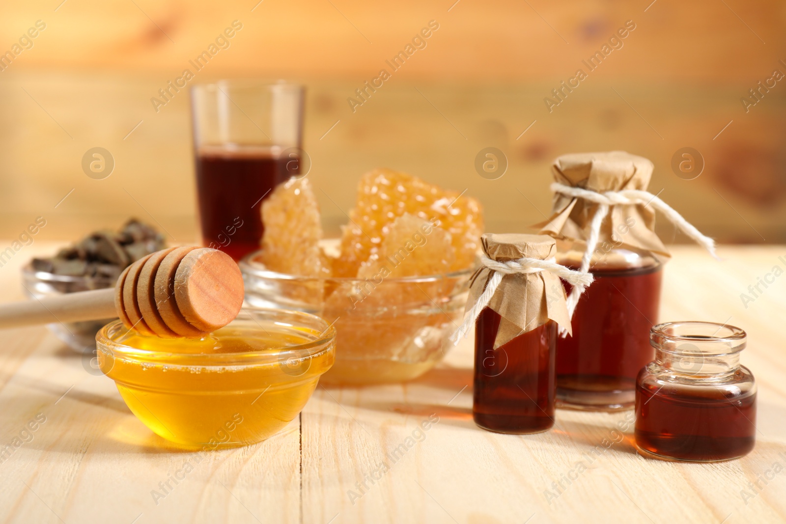 Photo of Honey, tincture and honeycombs on light wooden table, closeup. Alternative medicine