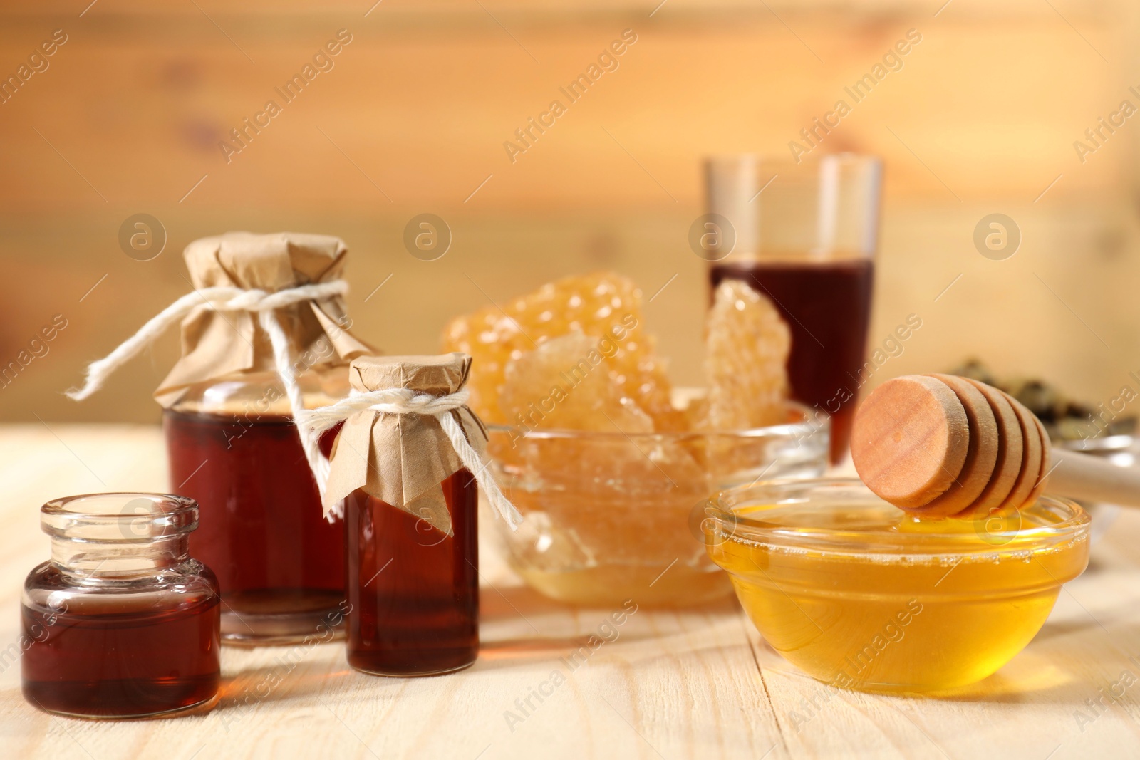 Photo of Honey, tincture and honeycombs on light wooden table, closeup. Alternative medicine