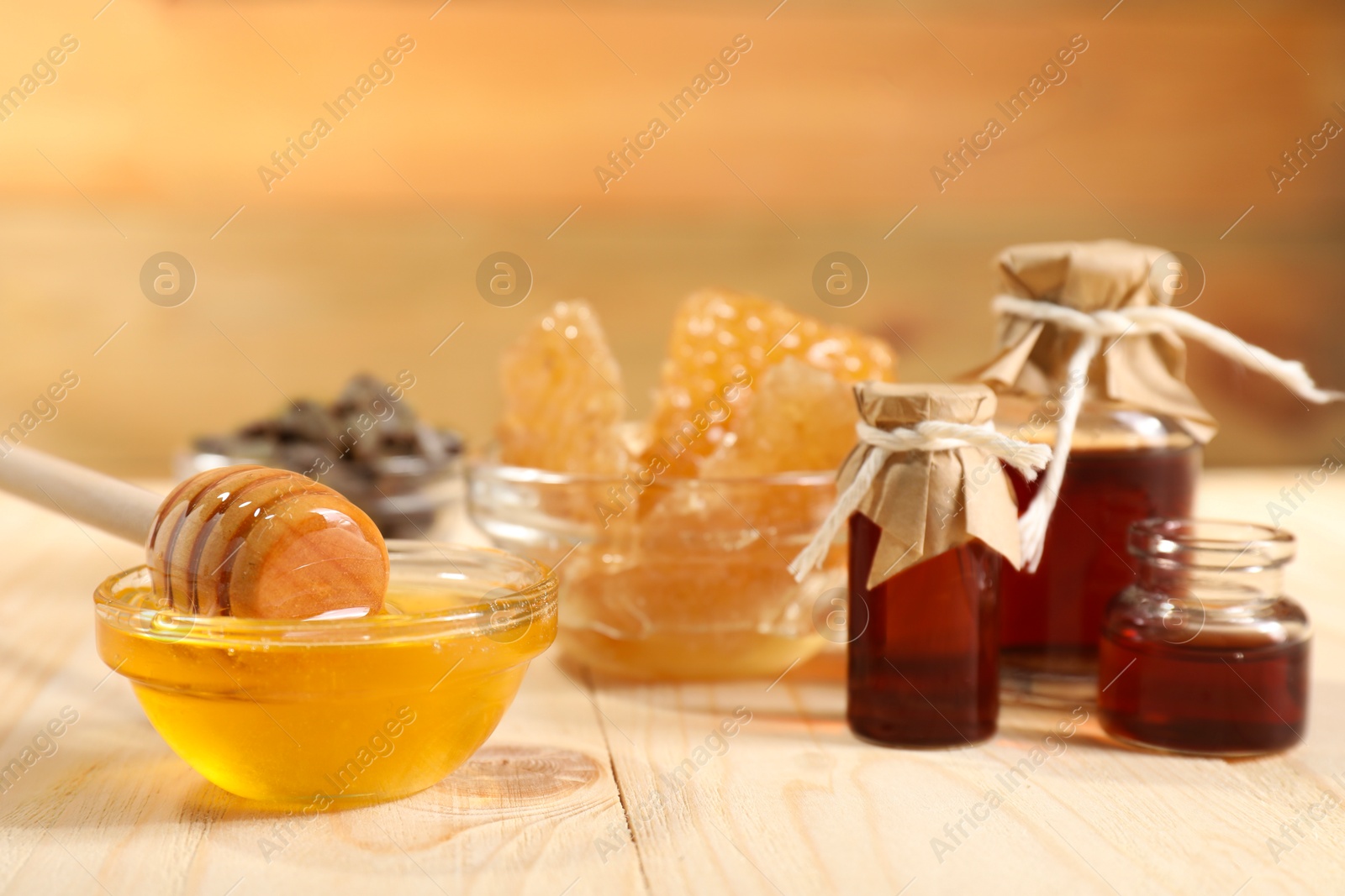 Photo of Honey, tincture and honeycombs on light wooden table, closeup. Alternative medicine