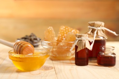 Photo of Honey, tincture and honeycombs on light wooden table, closeup. Alternative medicine