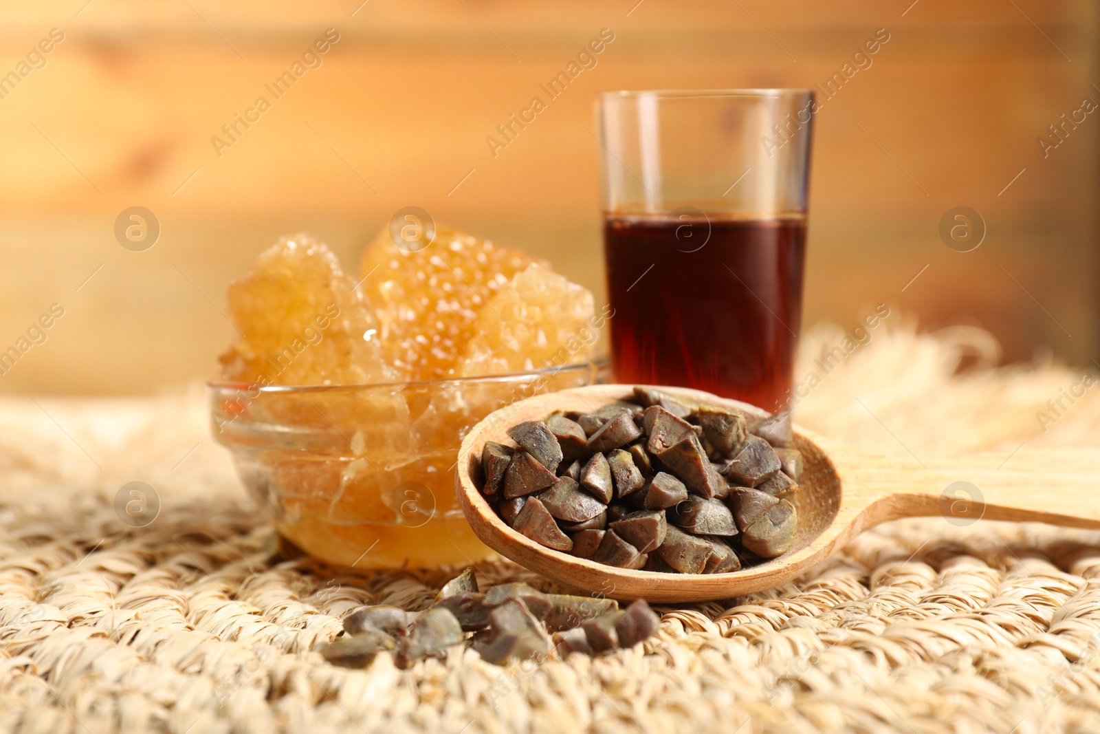 Photo of Spoon with propolis granules, honey tincture and honeycombs on table, closeup. Alternative medicine