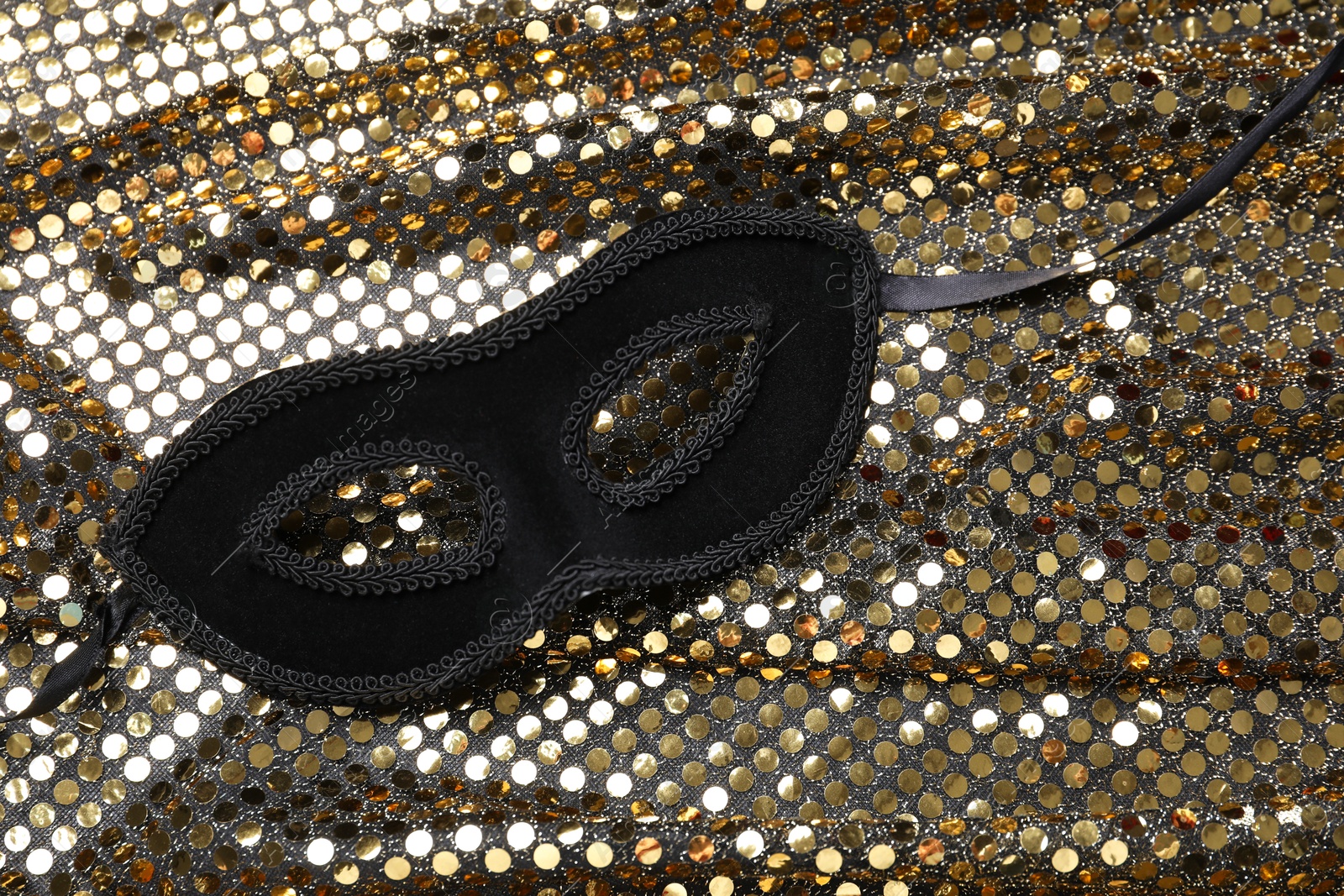 Photo of Beautiful carnival mask and fabric with golden sequins, top view