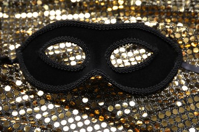 Photo of Beautiful carnival mask and fabric with golden sequins, closeup