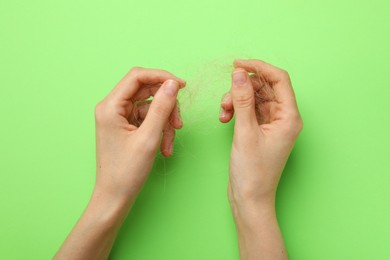 Photo of Woman with lost hair on light green background, top view. Alopecia problem