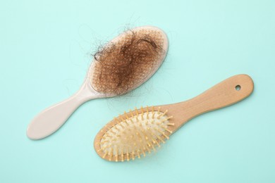 Photo of Brushes with lost hair on light blue background, flat lay. Alopecia problem