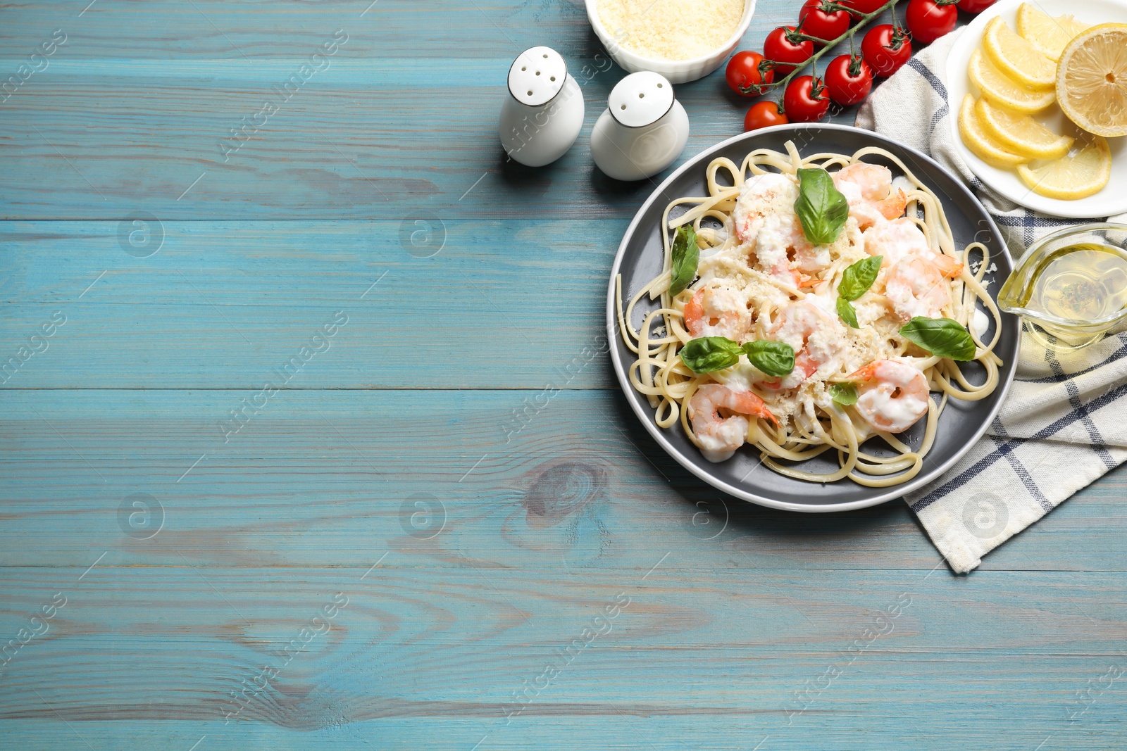 Photo of Tasty pasta with shrimps served on light blue wooden table, flat lay. Space for text